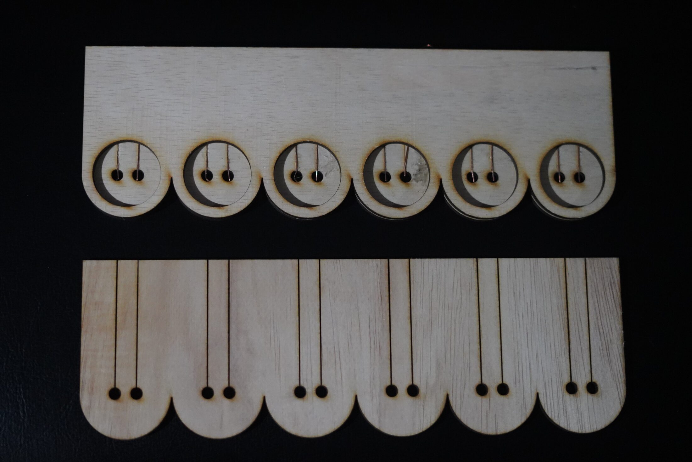 Flat-laid laser-cut wooden parts showing token discs and mounting pieces